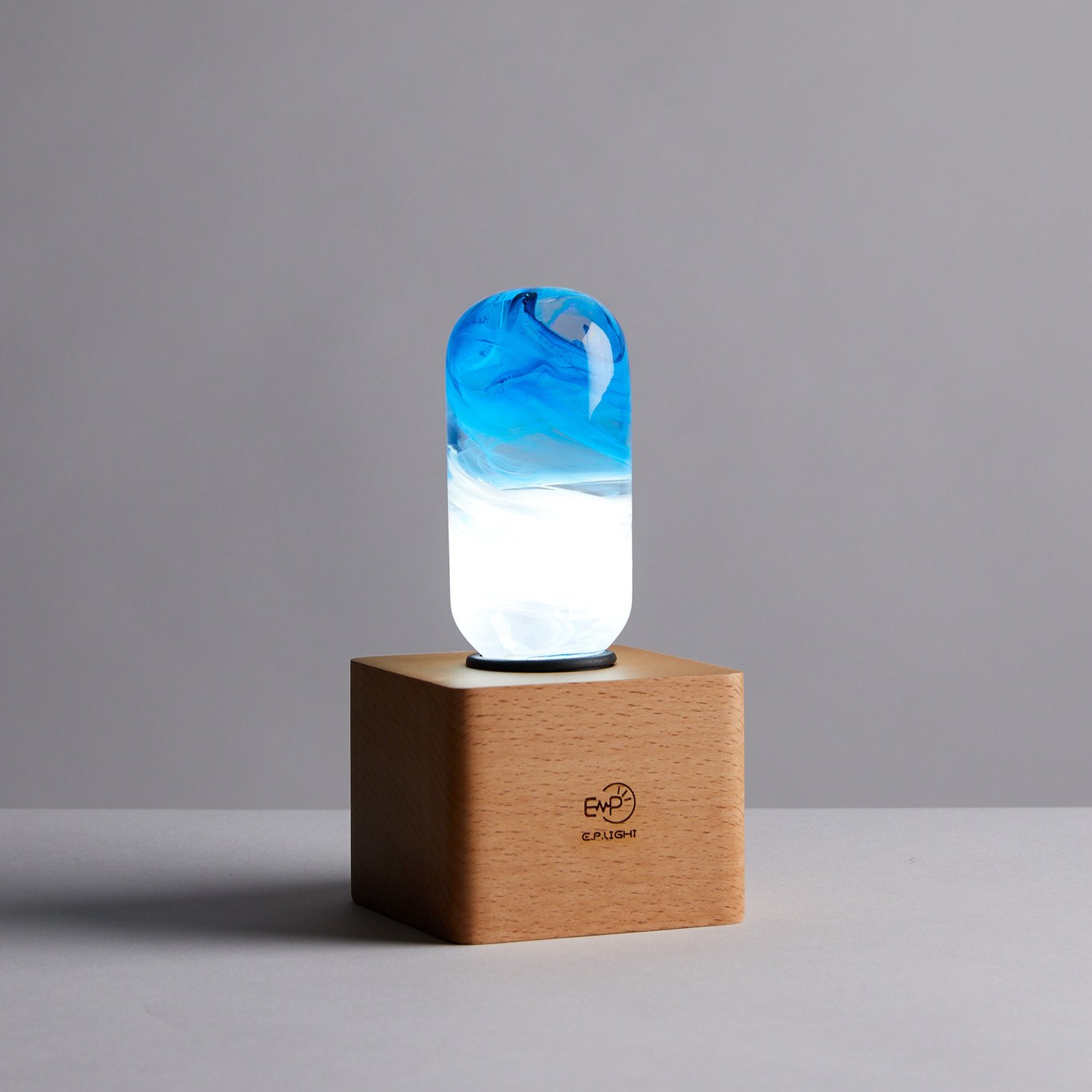 A stylish blue table lamp made from eco-friendly resin and beech wood, featuring an LED bulb and a modern design.