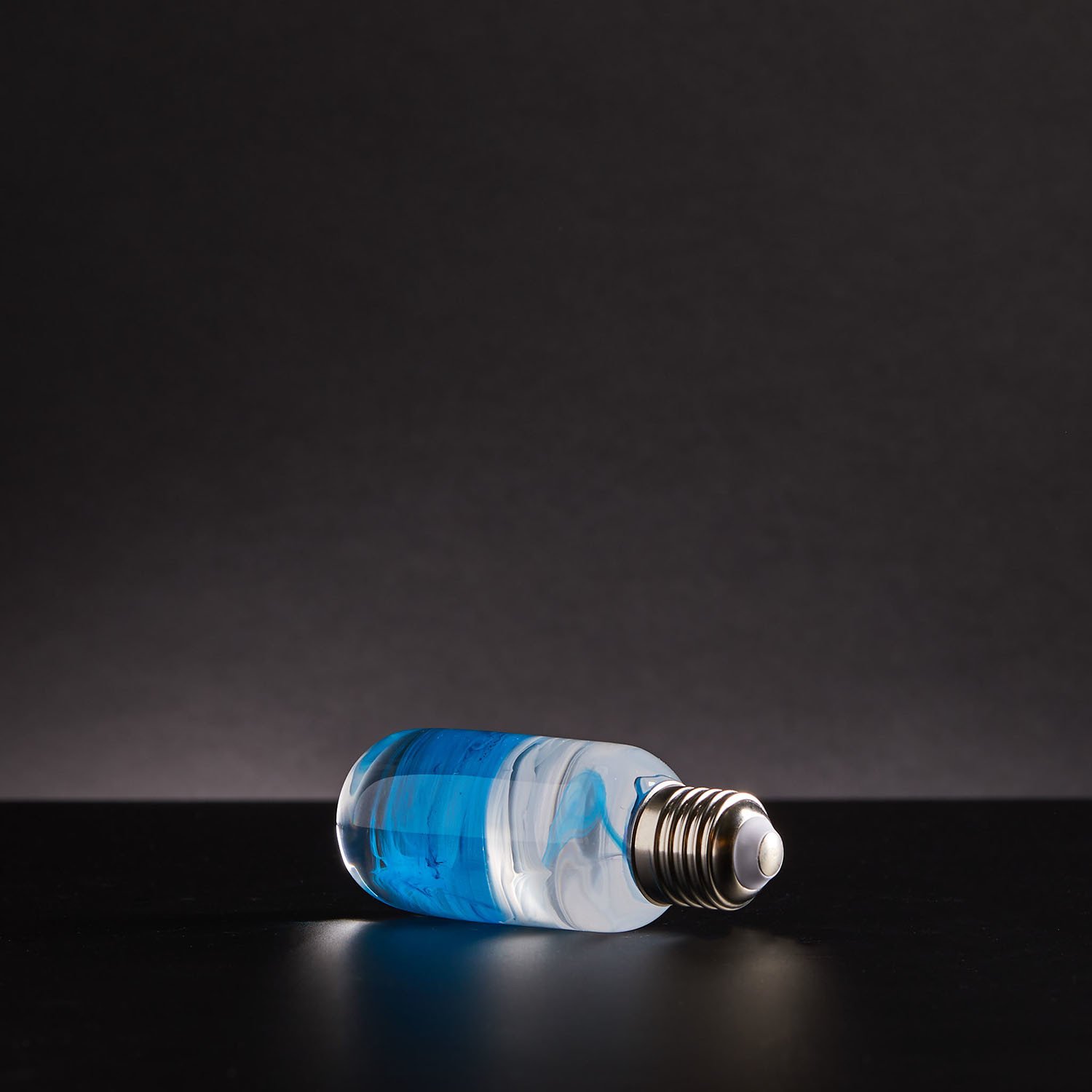 A stylish blue table lamp made from eco-friendly resin and beech wood, featuring an LED bulb and a modern design.