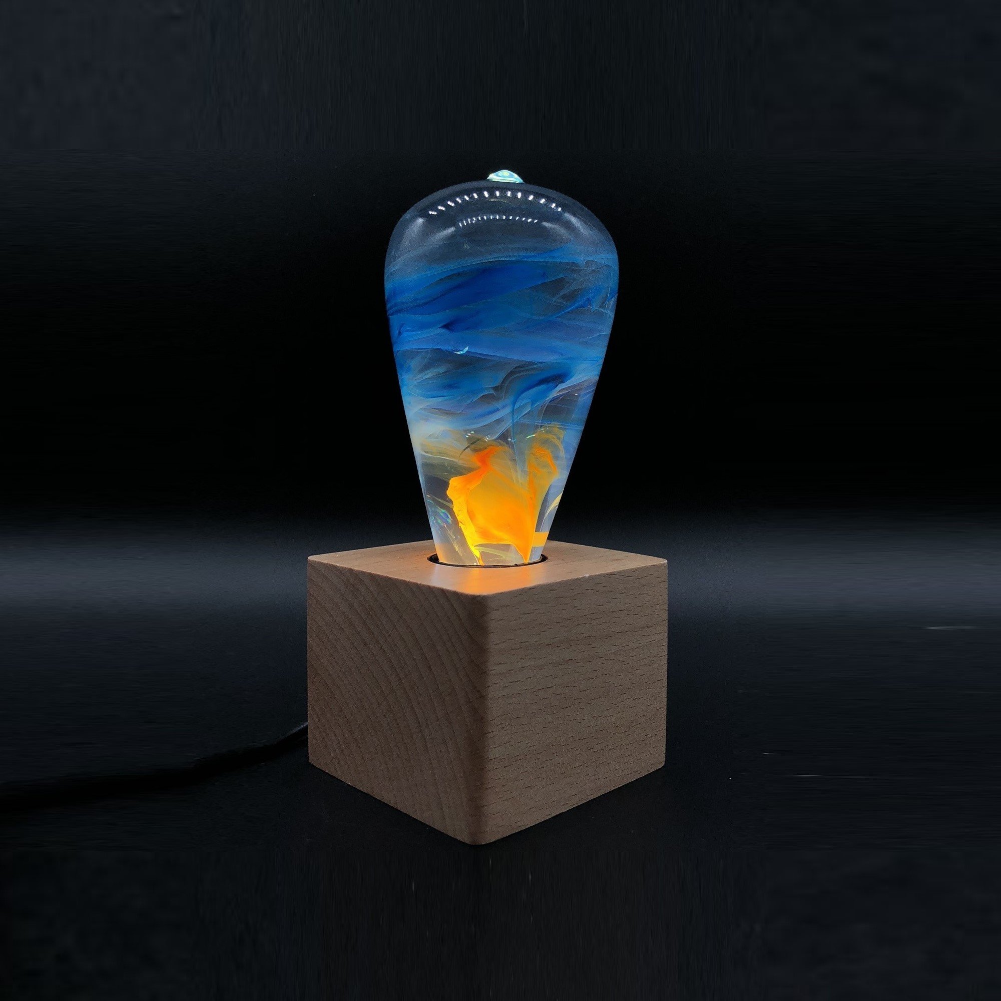 A beautifully handcrafted Fire Table Lamp made of eco-friendly resin and beech wood, featuring a vibrant mixed color design.