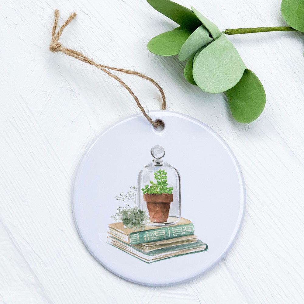 A beautifully crafted porcelain ornament featuring a terrarium and books design, showcasing vibrant colors and a glossy finish.