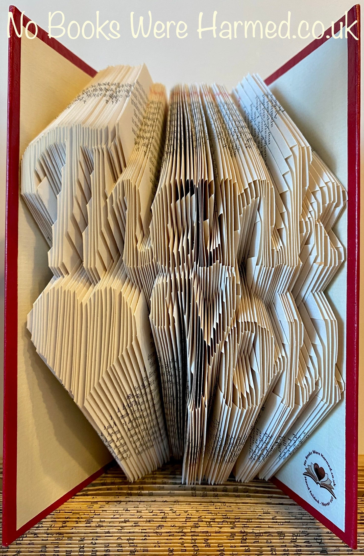 Handcrafted 'Thank You' art piece featuring a love heart, made from vintage book pages, showcasing unique folds and textures.