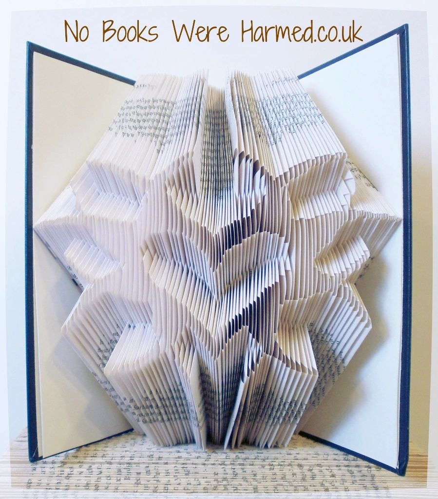 Handcrafted book art piece titled 'Heart Burst', featuring intricate folds creating a heart shape from vintage book pages.