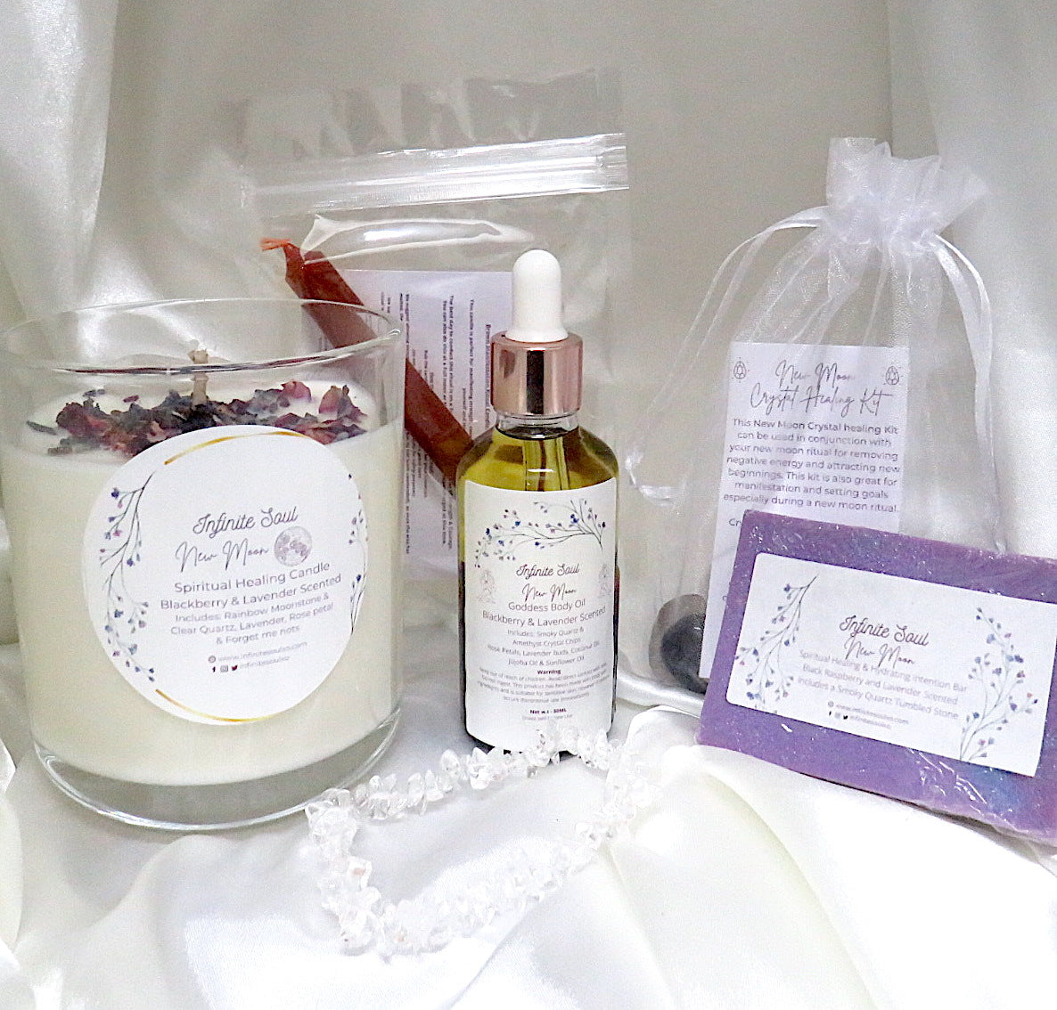 The Infinite Soul New Moon Bundle featuring a healing candle, body oil, crystal kit, soap, bracelet, and notebook, all designed for new moon rituals.