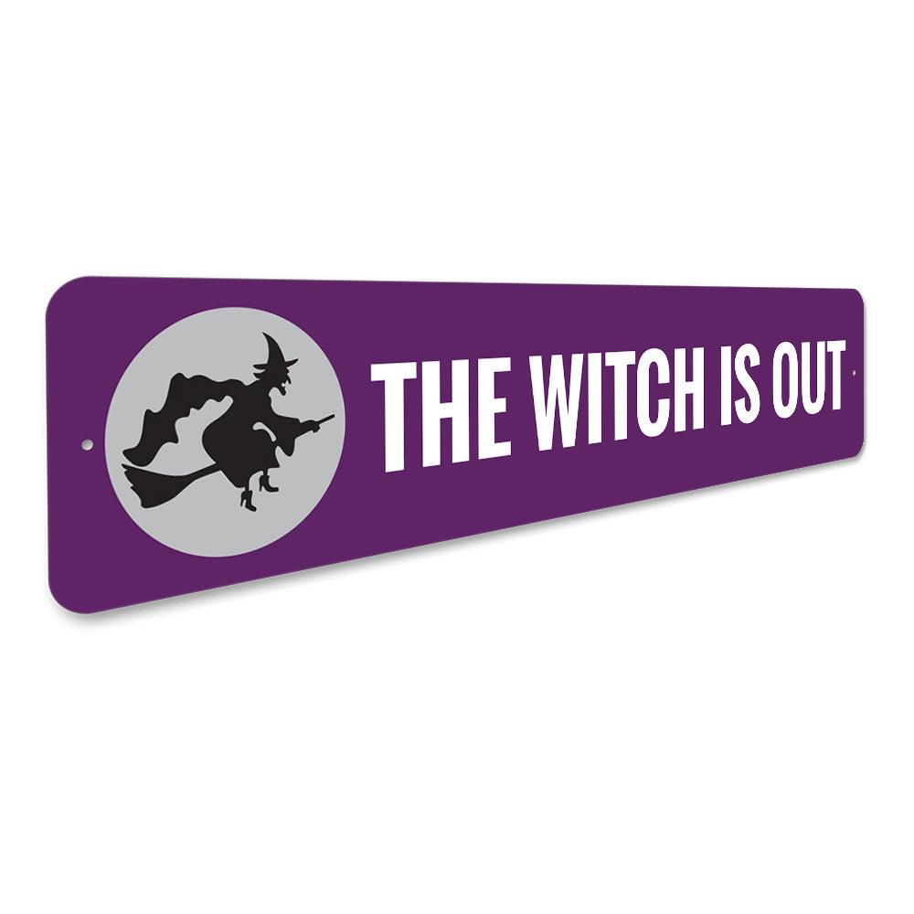 A decorative Halloween sign reading 'The Witch is OUT', made of high-quality aluminum, featuring spooky design elements.