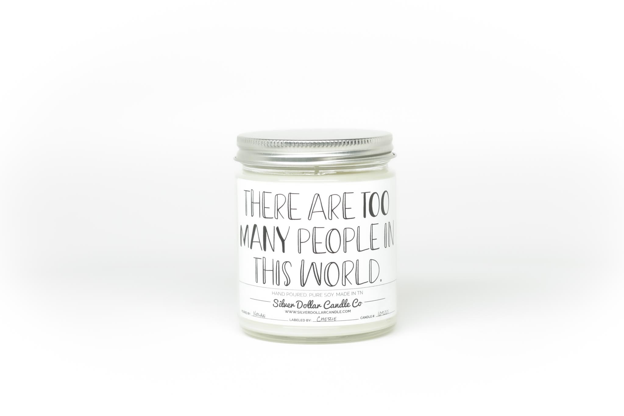 A humorous candle labeled 'There Are Too Many People In The World', showcasing its stylish design and available scents.