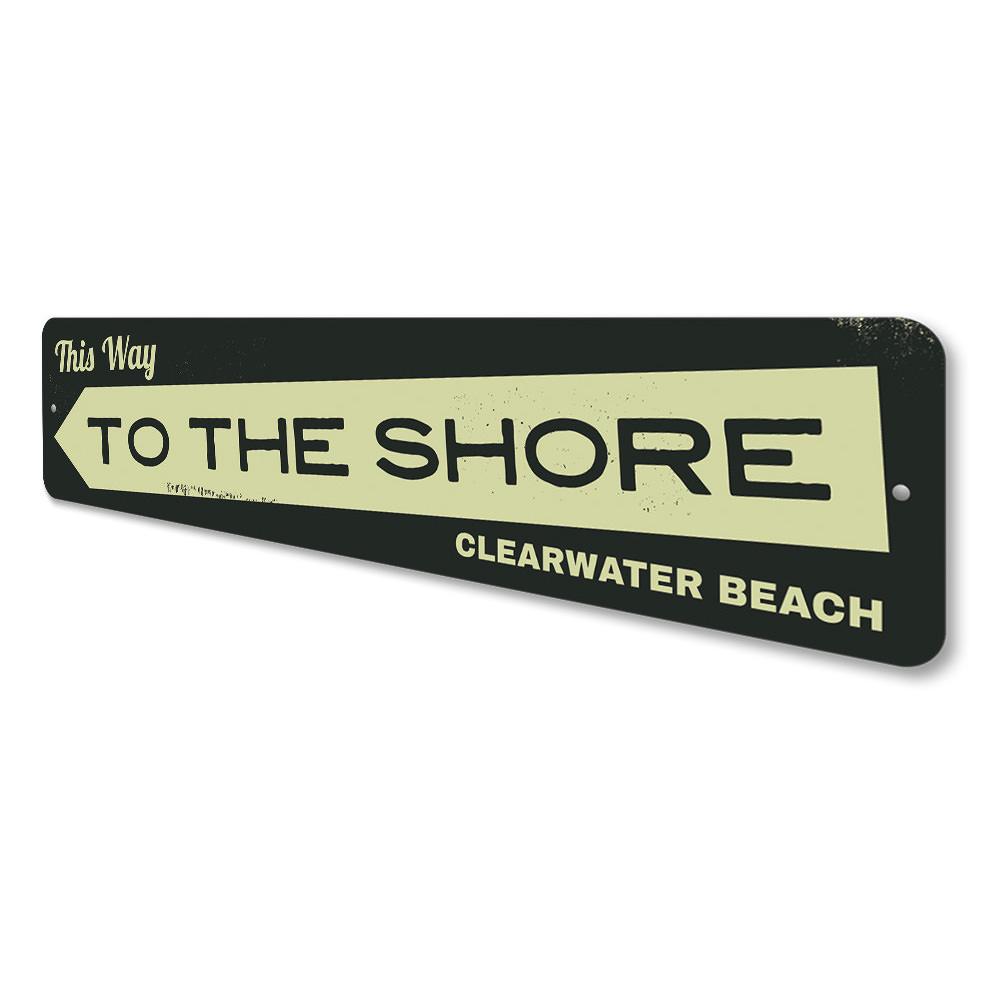 A decorative metal sign reading 'This Way to the Shore', featuring a coastal design, perfect for beach houses and coastal decor.