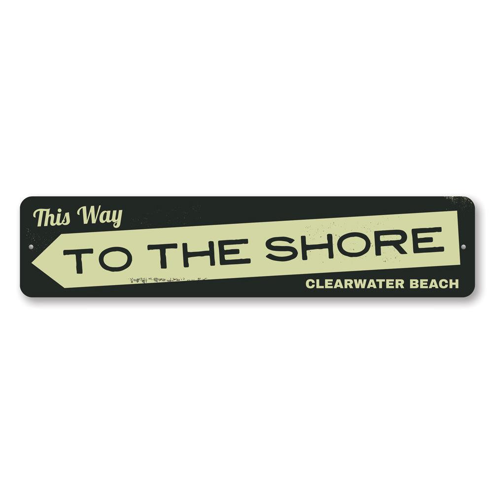 A decorative metal sign reading 'This Way to the Shore', featuring a coastal design, perfect for beach houses and coastal decor.