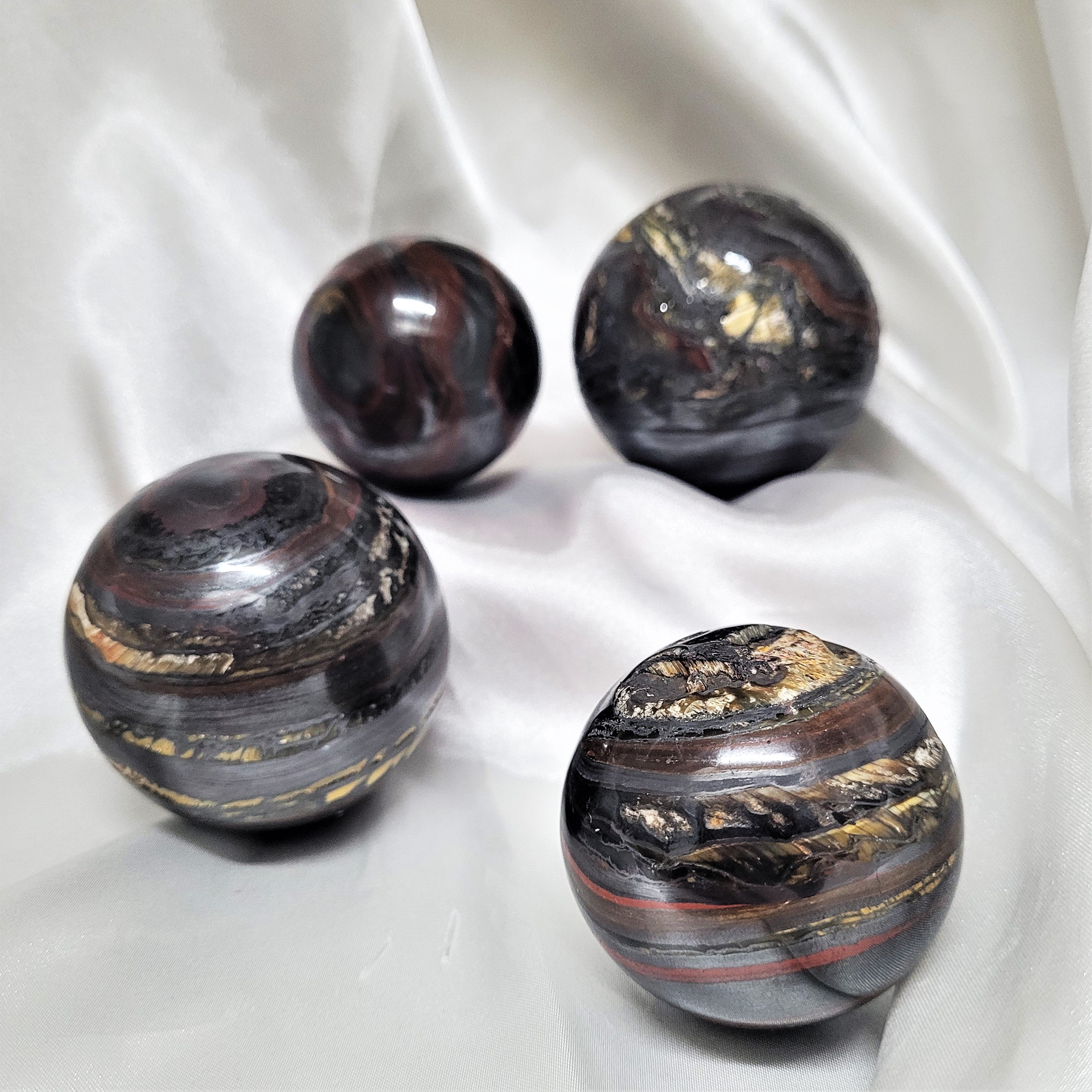 A beautifully hand-carved Tiger Iron Sphere showcasing its unique banded layers of Hematite, Red Jasper, and Tiger Eye.