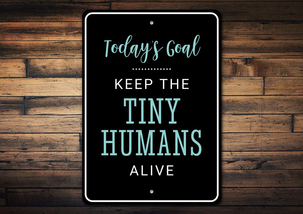 A decorative Tiny Humans Sign made of high-quality aluminum, featuring customizable text and pre-drilled holes for easy mounting.