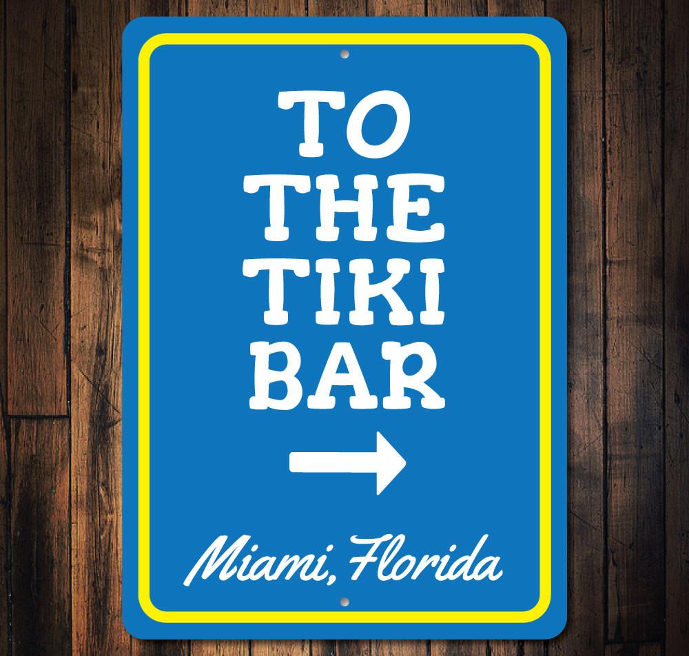 A decorative 'To the Tiki Bar' sign made of high-quality aluminum, featuring vibrant colors and a beach-themed design, perfect for coastal decor.