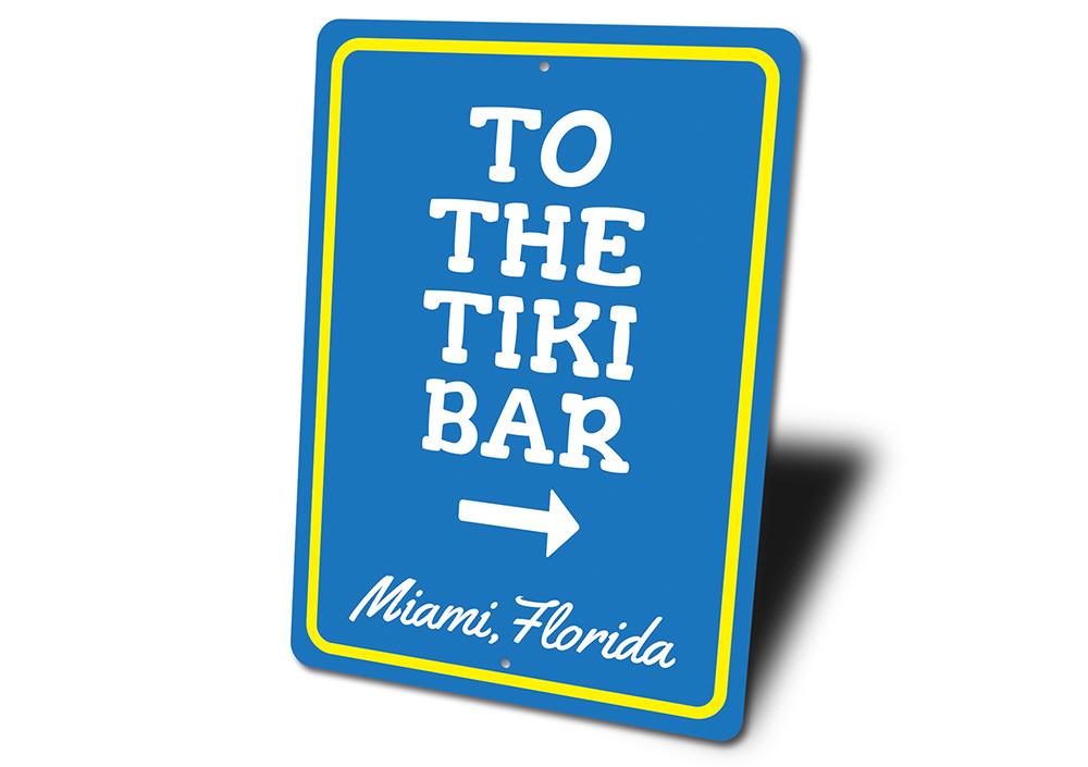 A decorative 'To the Tiki Bar' sign made of high-quality aluminum, featuring vibrant colors and a beach-themed design, perfect for coastal decor.