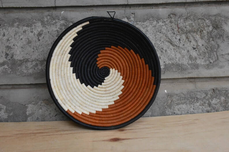 Traditional African Coiled Raffia Basket handcrafted from dyed raffia and banana stalks, featuring unique colors and patterns.