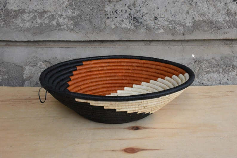 Traditional African Coiled Raffia Basket handcrafted from dyed raffia and banana stalks, featuring unique colors and patterns.