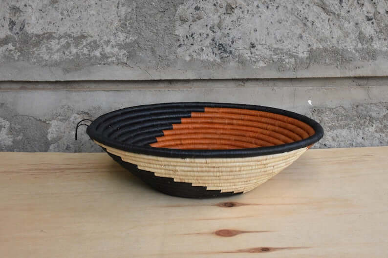 Traditional African Coiled Raffia Basket handcrafted from dyed raffia and banana stalks, featuring unique colors and patterns.