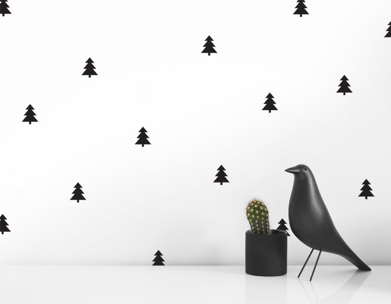 A collection of 25 black and gray tree wall decals arranged on a smooth wall, showcasing their design and versatility.