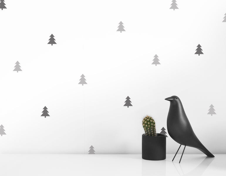 A collection of 25 black and gray tree wall decals arranged on a smooth wall, showcasing their design and versatility.