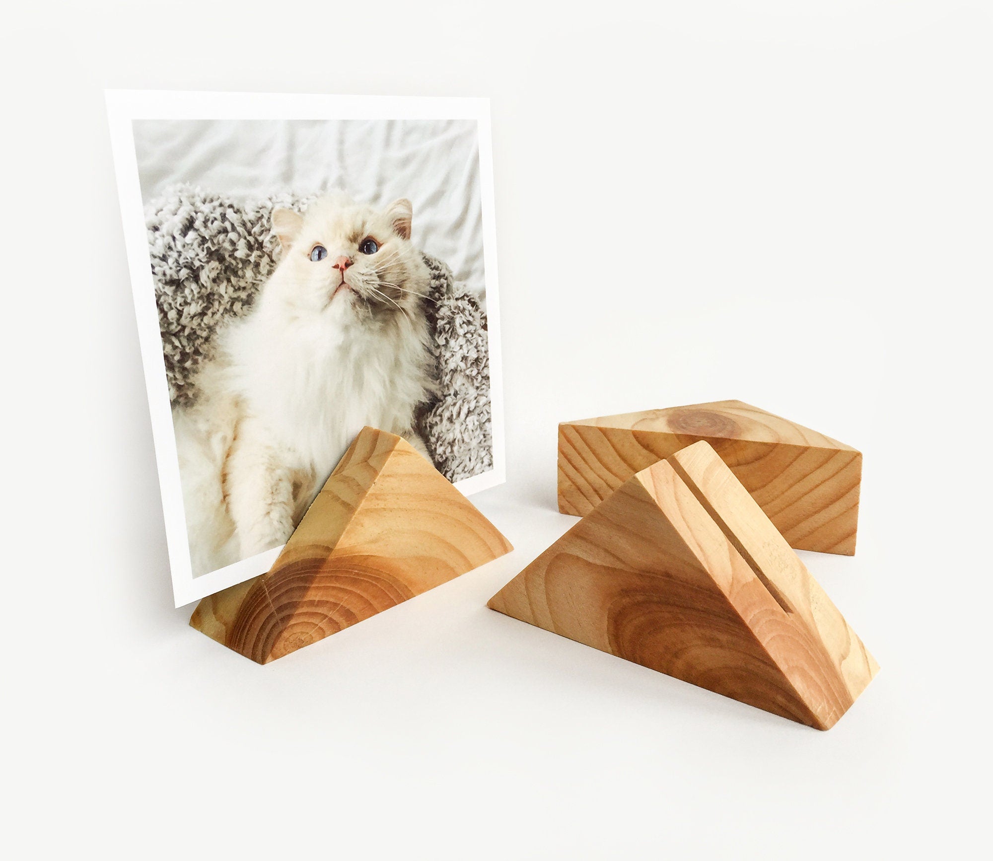 A beautifully handcrafted triangle wood card holder displaying various art prints and photos, showcasing its eco-friendly design and versatility.