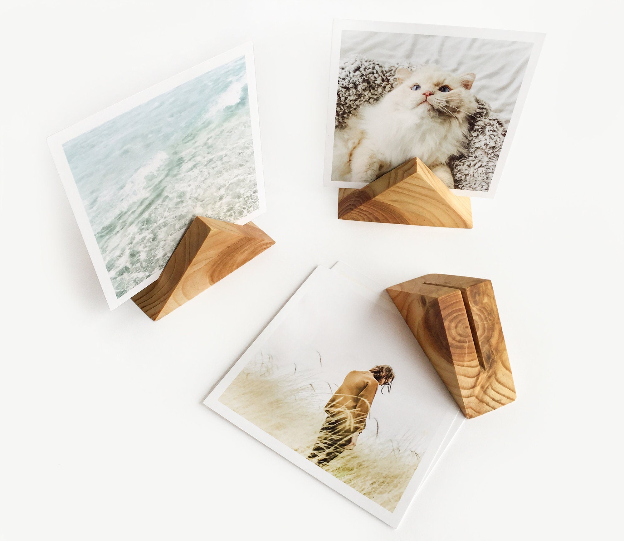 A beautifully handcrafted triangle wood card holder displaying various art prints and photos, showcasing its eco-friendly design and versatility.