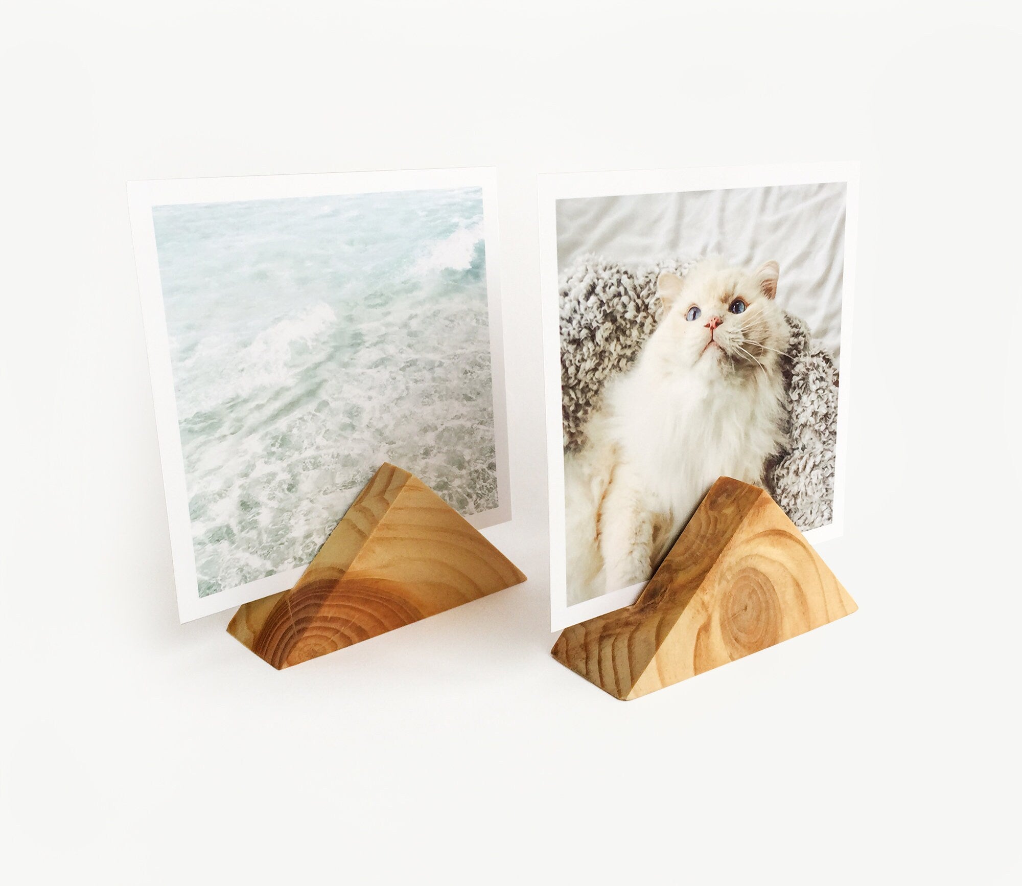 A beautifully handcrafted triangle wood card holder displaying various art prints and photos, showcasing its eco-friendly design and versatility.