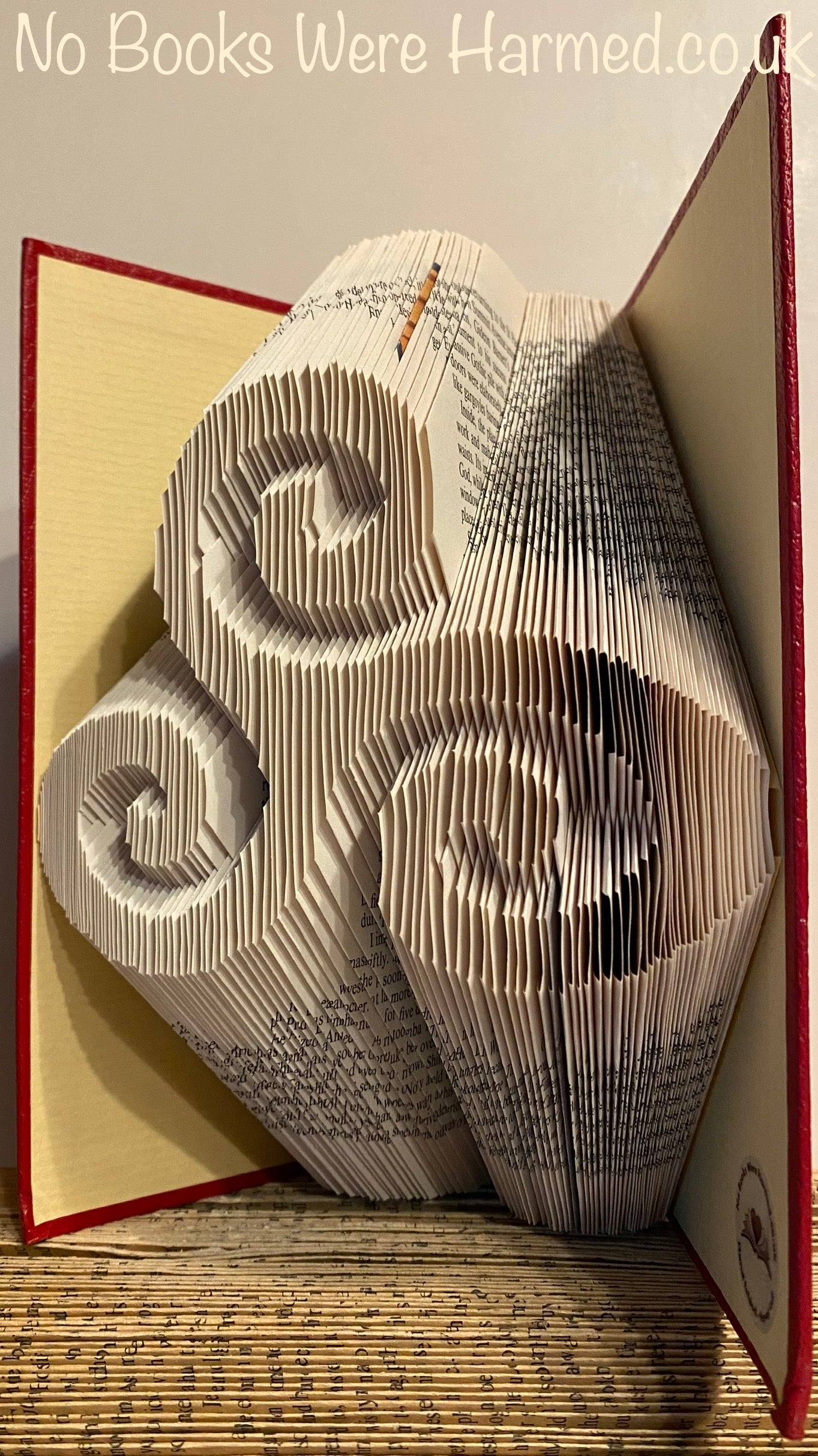 Handcrafted Triskelion art piece made from vintage book pages, showcasing intricate folded designs in various colors.