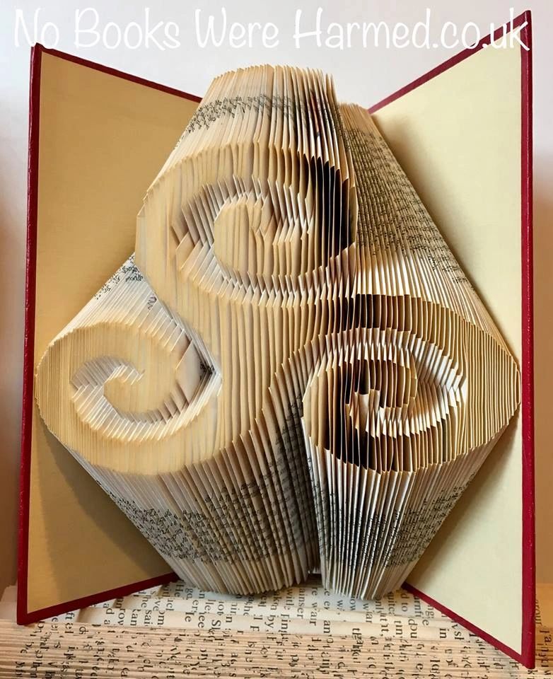 Handcrafted Triskelion art piece made from vintage book pages, showcasing intricate folded designs in various colors.