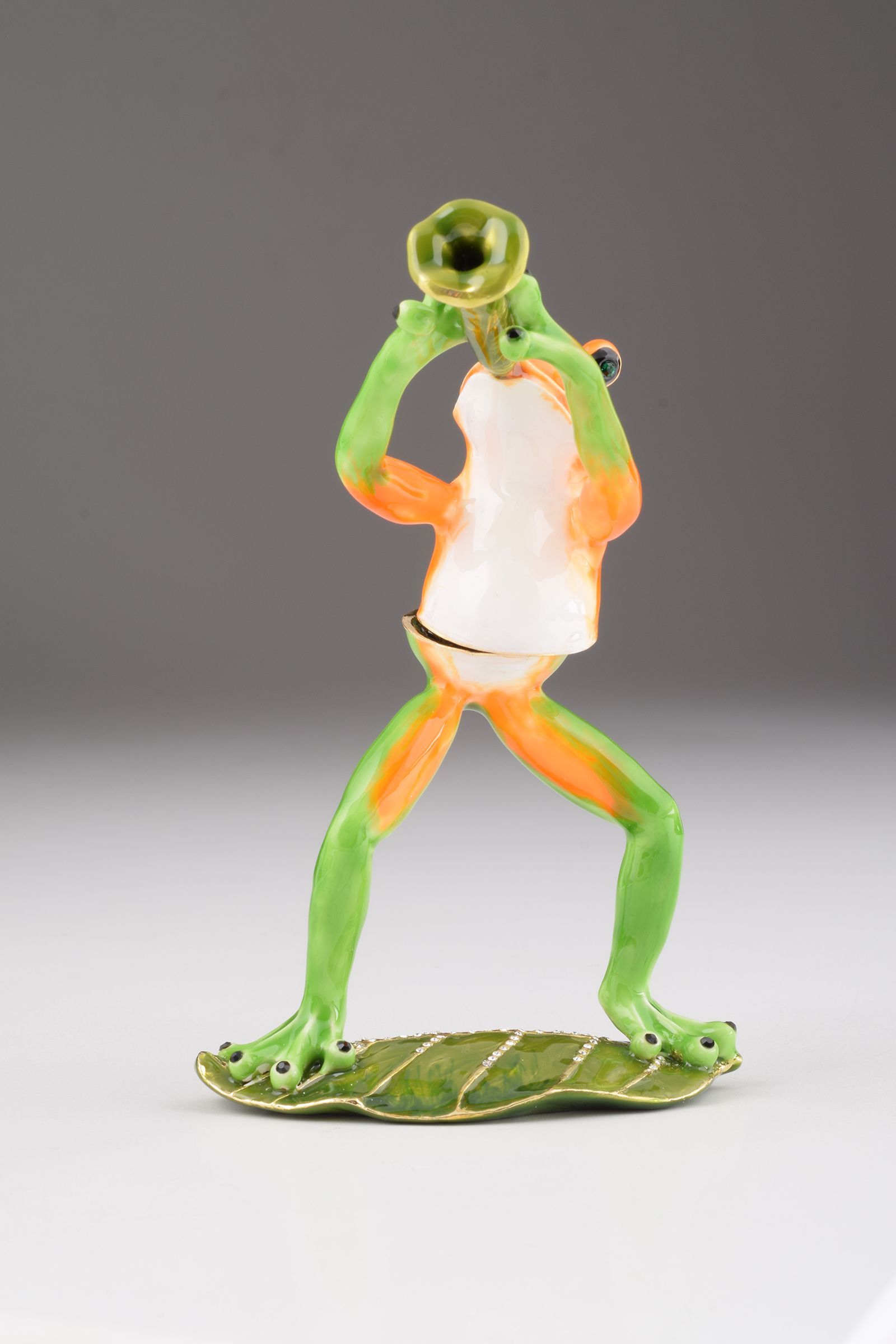 A beautifully crafted Trumpet Playing Frog trinket box, featuring vibrant enamel and sparkling Austrian crystals, plated with 24K gold.