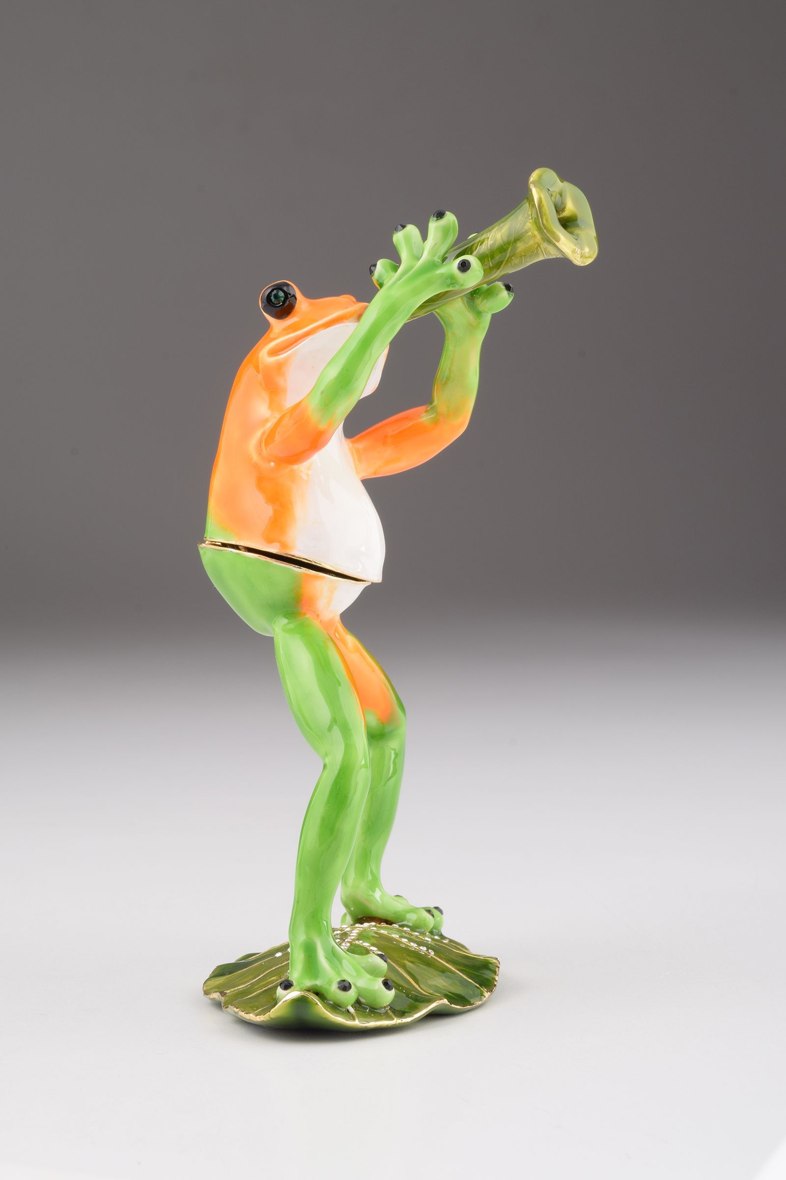 A beautifully crafted Trumpet Playing Frog trinket box, featuring vibrant enamel and sparkling Austrian crystals, plated with 24K gold.