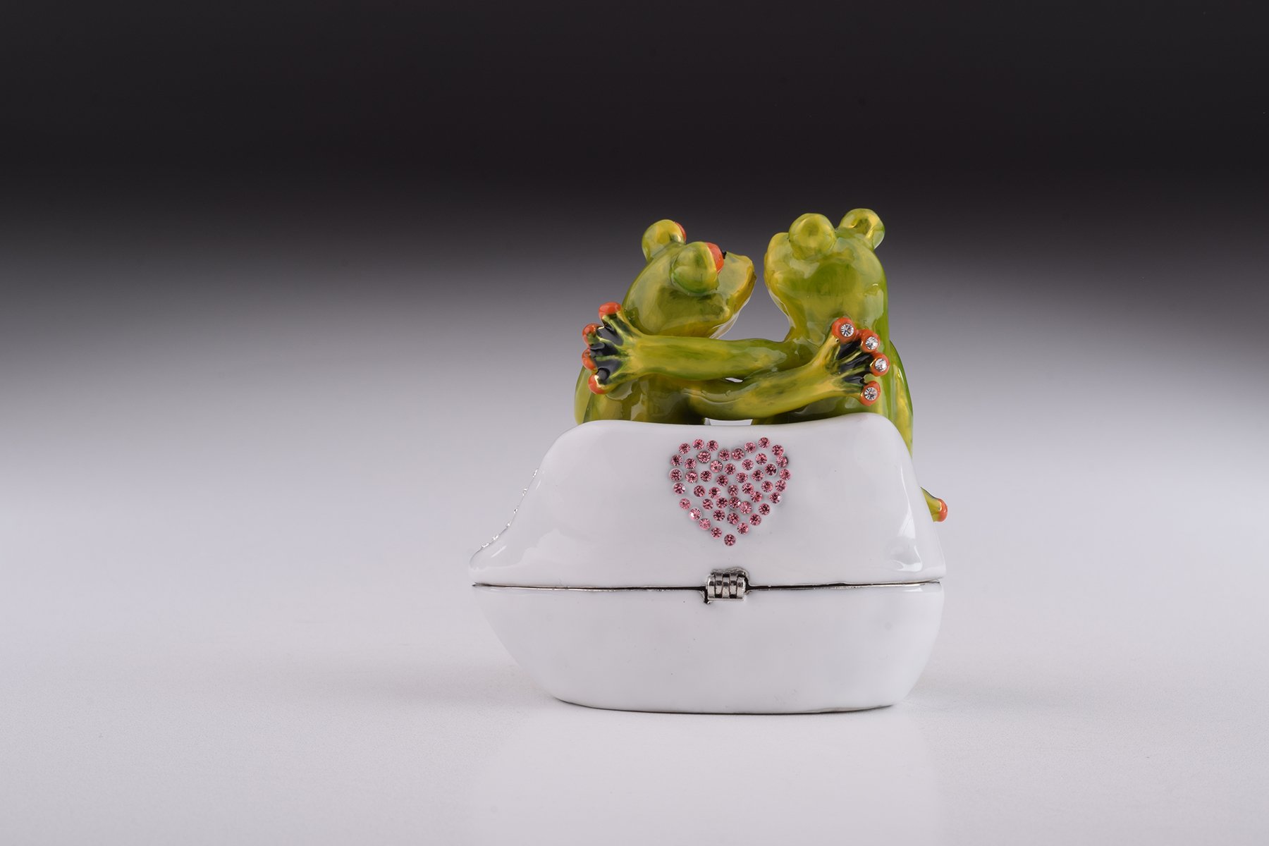 A beautifully crafted enamel trinket box featuring two frogs in love, adorned with sparkling Austrian crystals and plated with 24K gold.