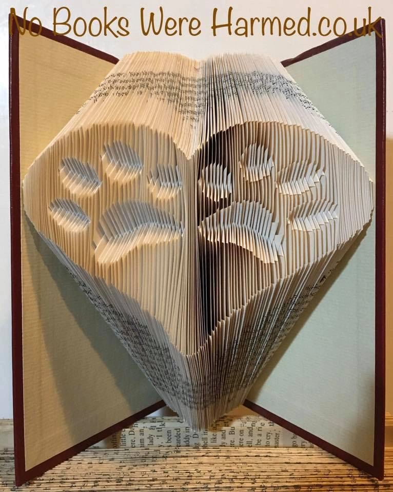 Handcrafted book art featuring two inverted paws within a heart, made from vintage book pages.