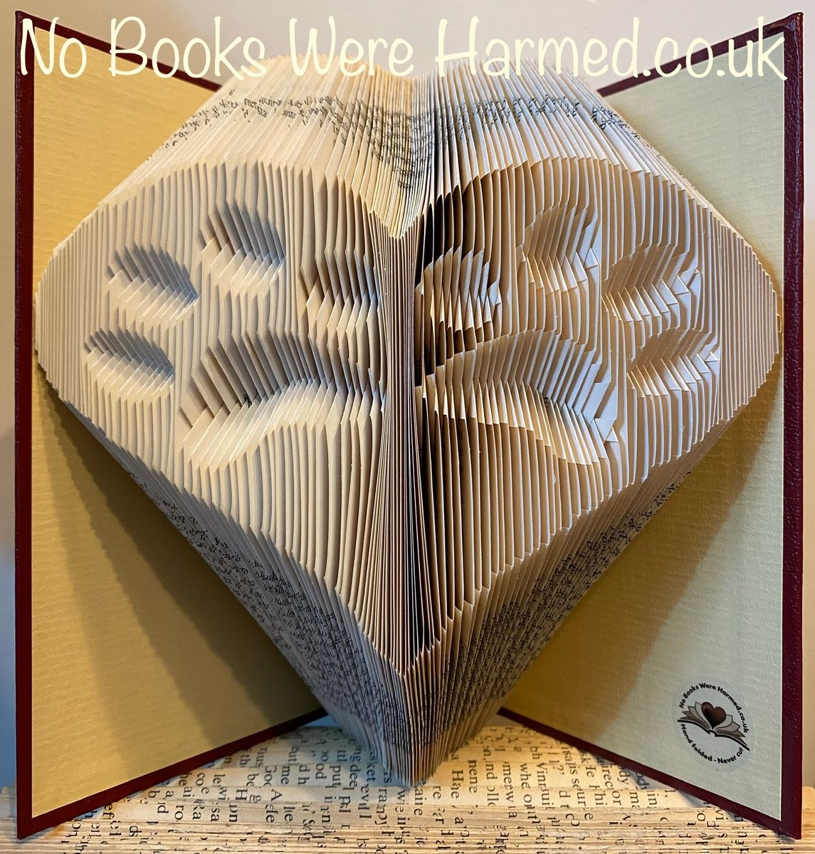 Handcrafted book art featuring two inverted paws within a heart, made from vintage book pages.