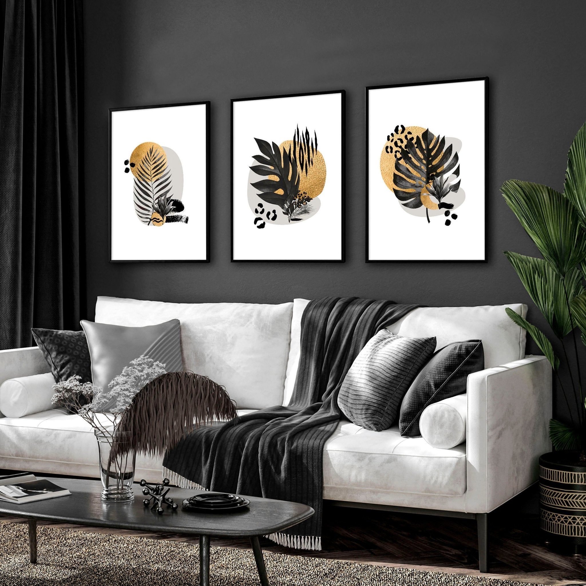 Set of 3 framed wall art prints featuring tropical botanical designs in gold, black, and grey, perfect for living room decor.