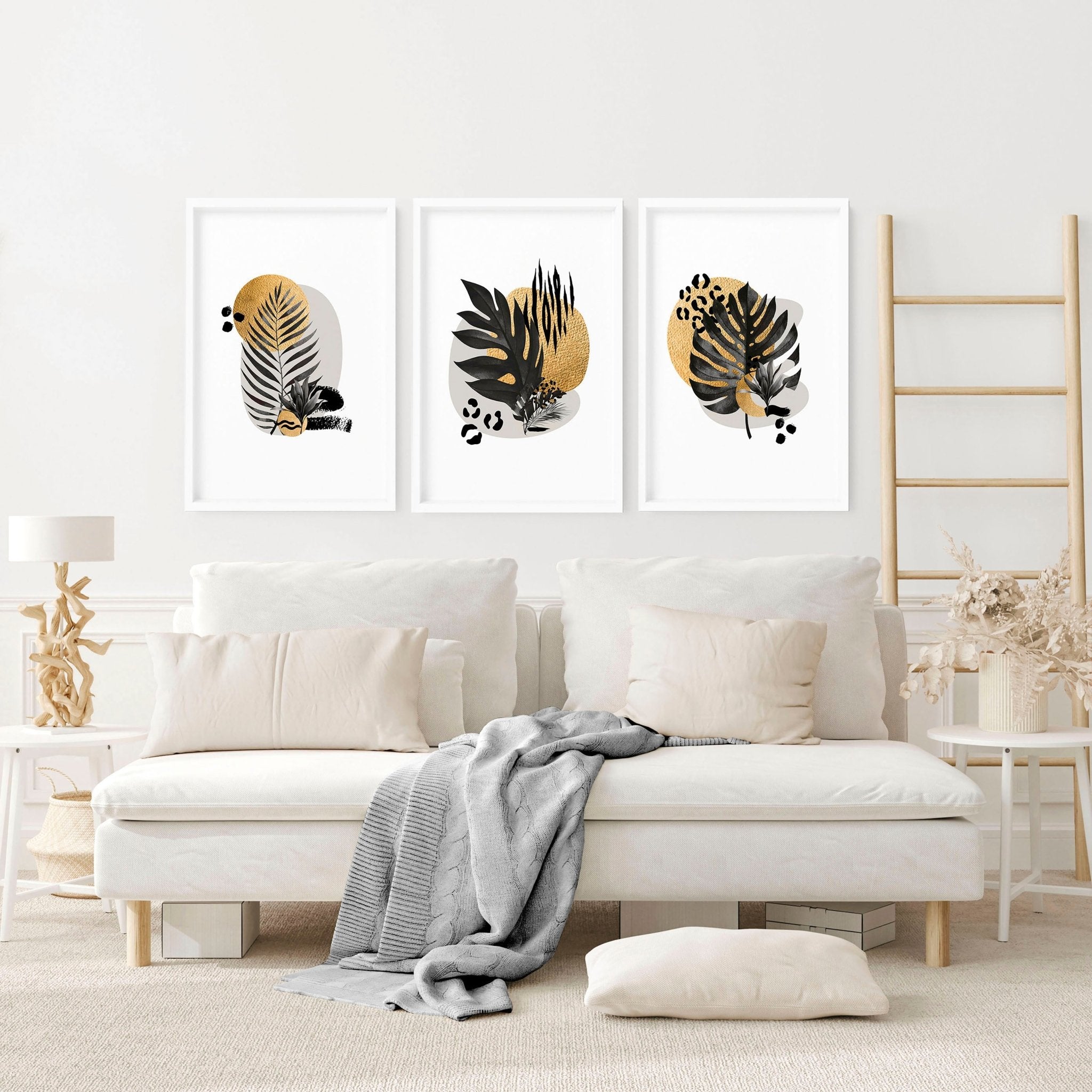 Set of 3 framed wall art prints featuring tropical botanical designs in gold, black, and grey, perfect for living room decor.