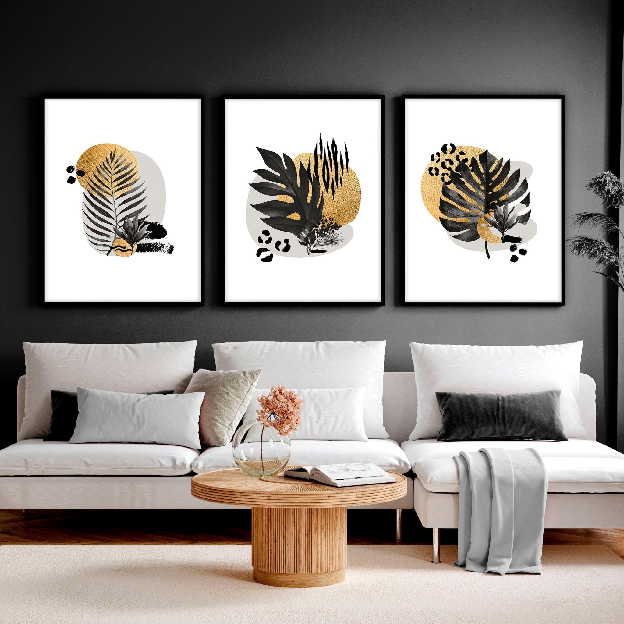 Set of 3 framed wall art prints featuring tropical botanical designs in gold, black, and grey, perfect for living room decor.