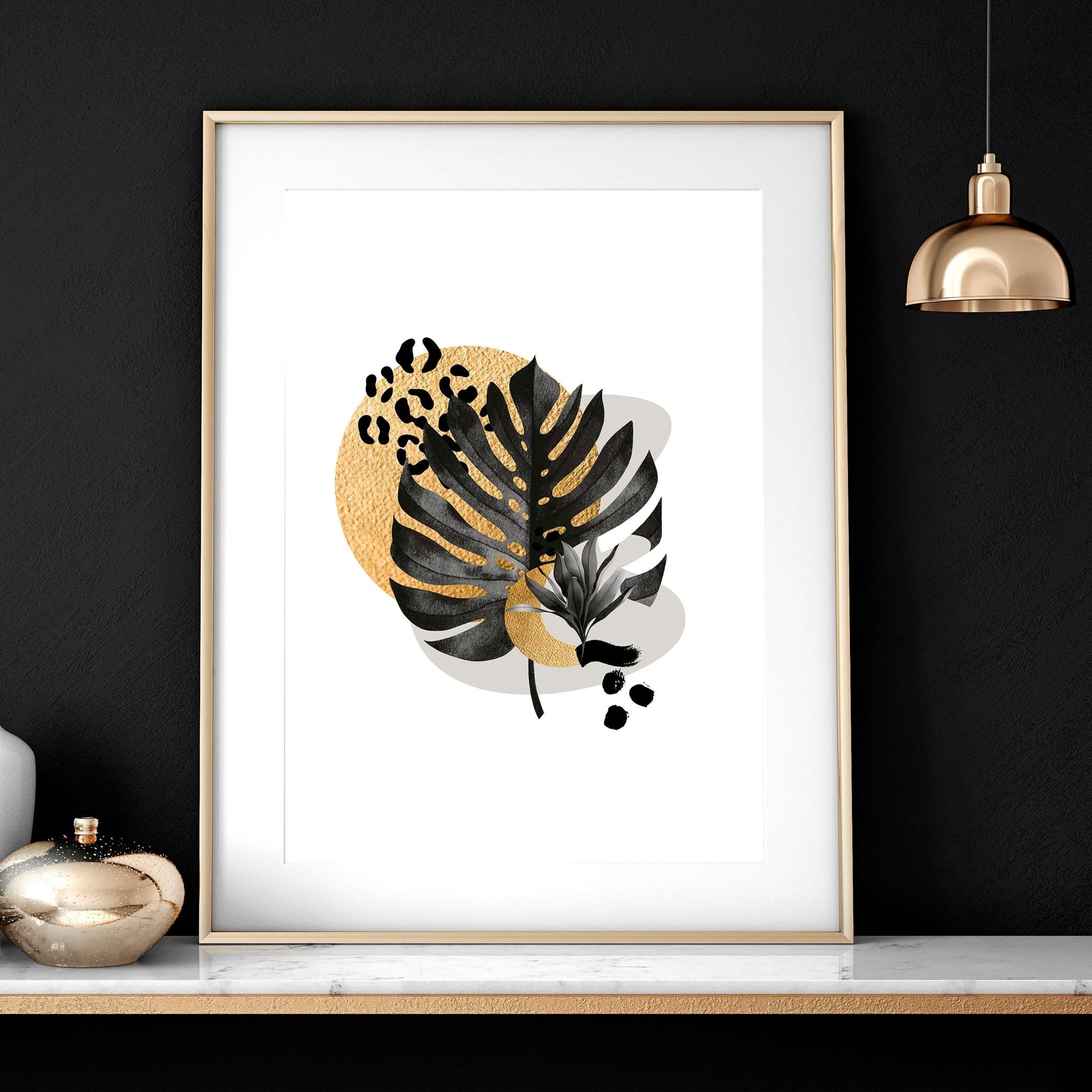 Set of 3 framed wall art prints featuring tropical botanical designs in gold, black, and grey, perfect for living room decor.