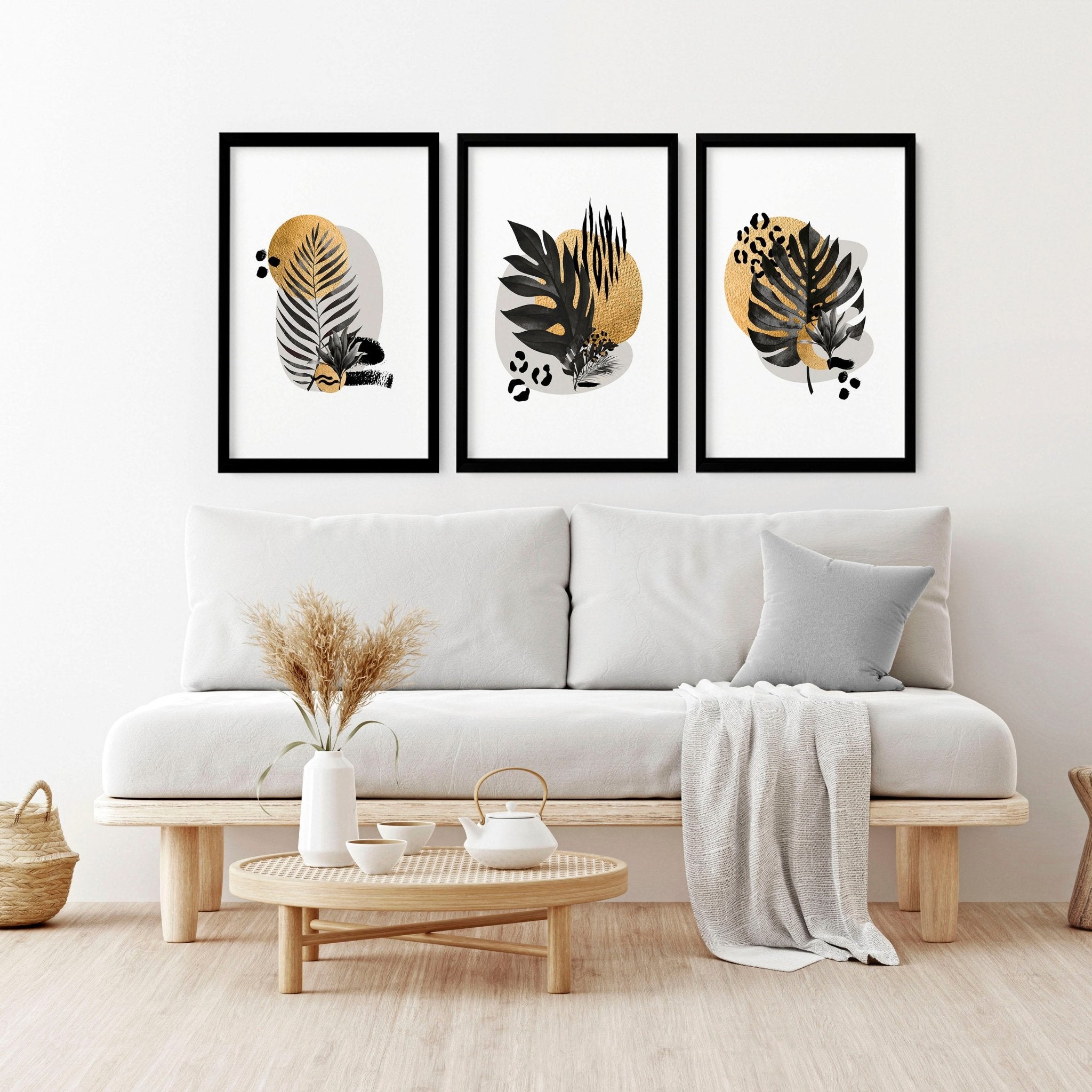 Set of 3 framed wall art prints featuring tropical botanical designs in gold, black, and grey, perfect for living room decor.