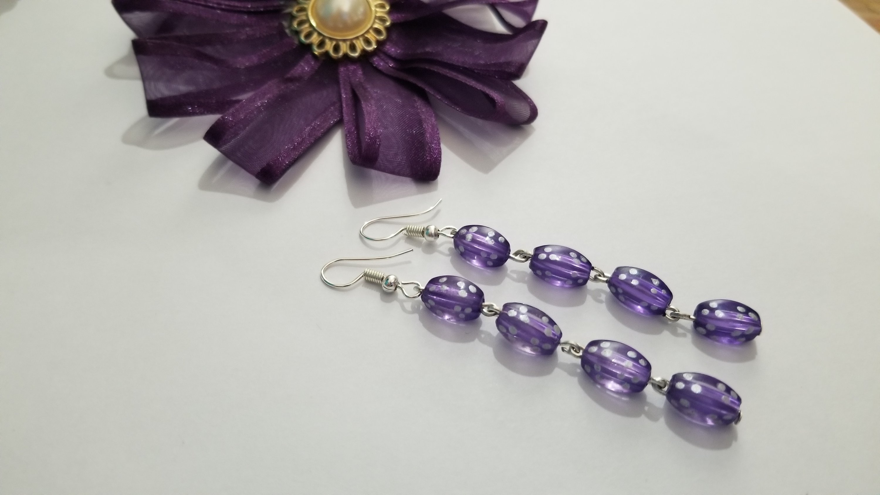 A pair of elegant violet long earrings with a translucent finish, showcasing their stylish design and lightweight structure.