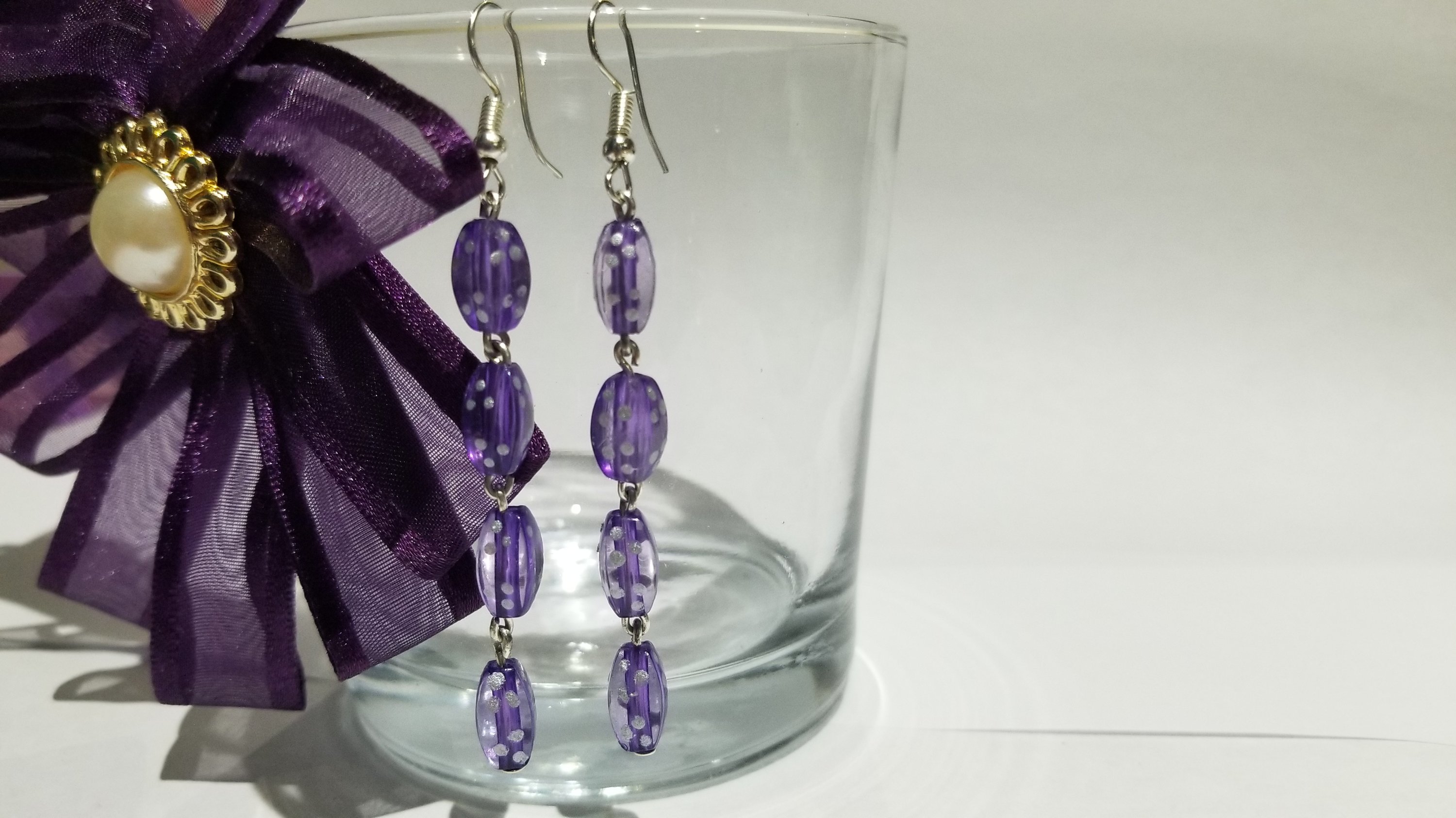 A pair of elegant violet long earrings with a translucent finish, showcasing their stylish design and lightweight structure.