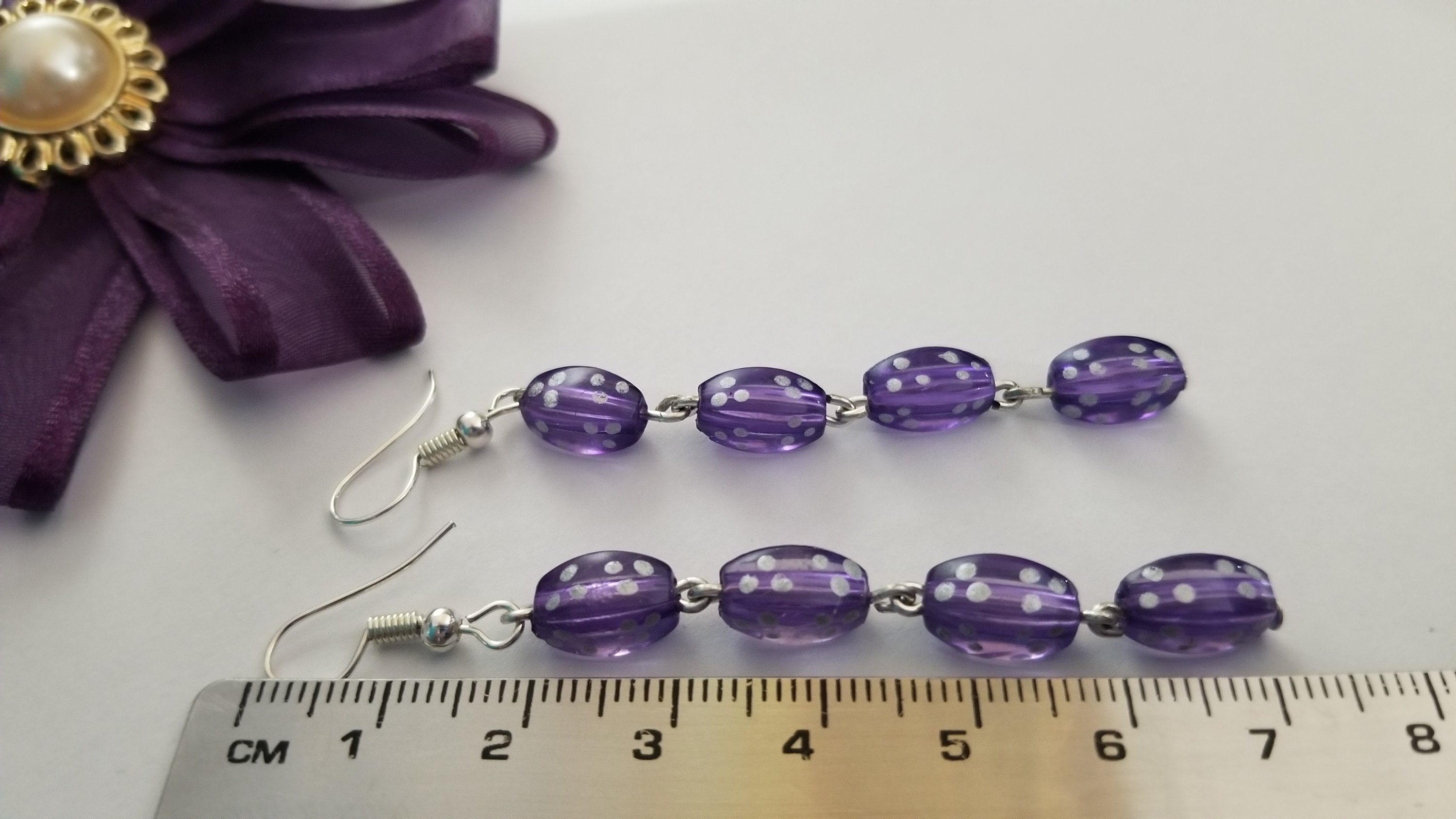 A pair of elegant violet long earrings with a translucent finish, showcasing their stylish design and lightweight structure.