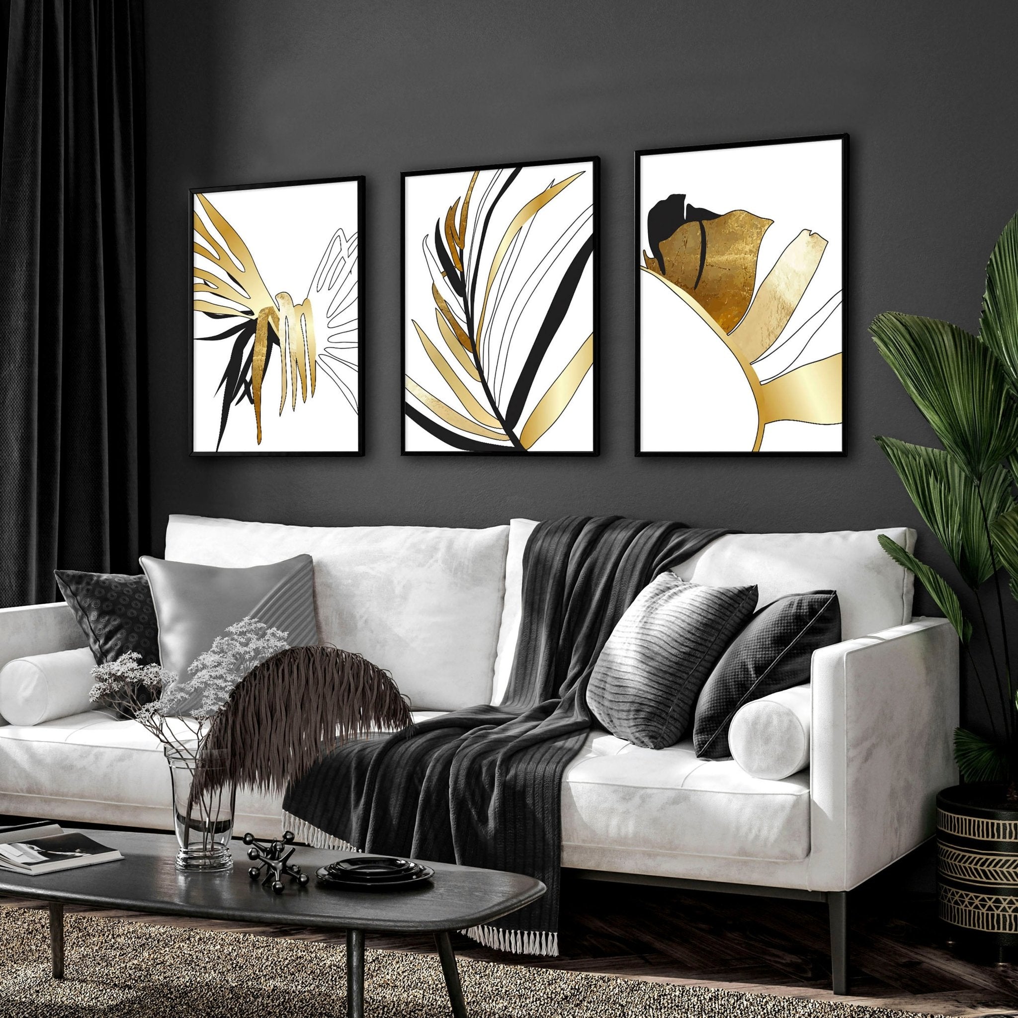 Set of 3 modern tropical wall art prints featuring elegant botanical designs in white, black, and gold, perfect for living room decor.