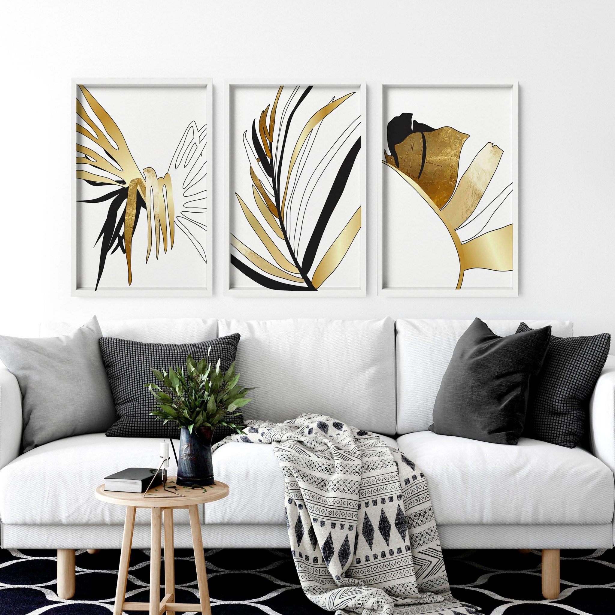 Set of 3 modern tropical wall art prints featuring elegant botanical designs in white, black, and gold, perfect for living room decor.