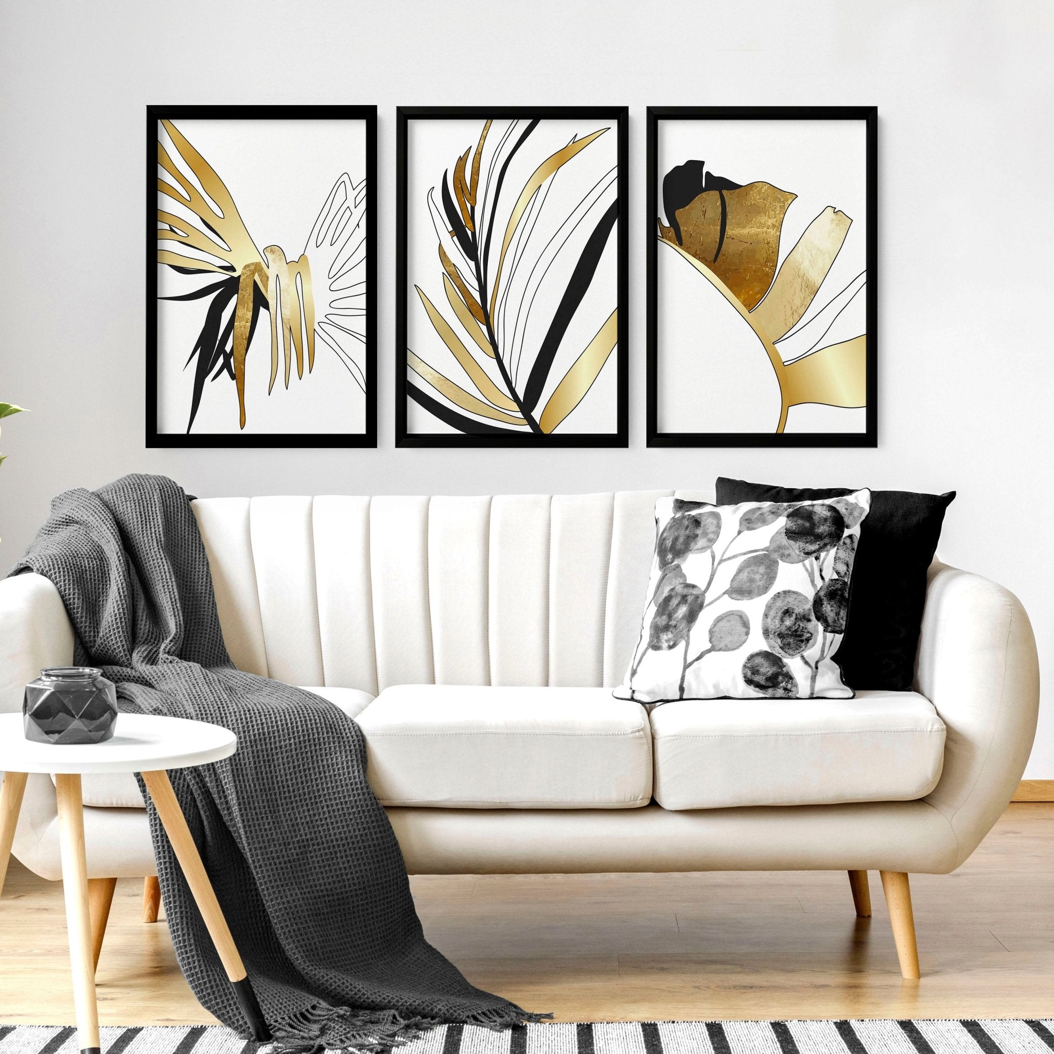 Set of 3 modern tropical wall art prints featuring elegant botanical designs in white, black, and gold, perfect for living room decor.