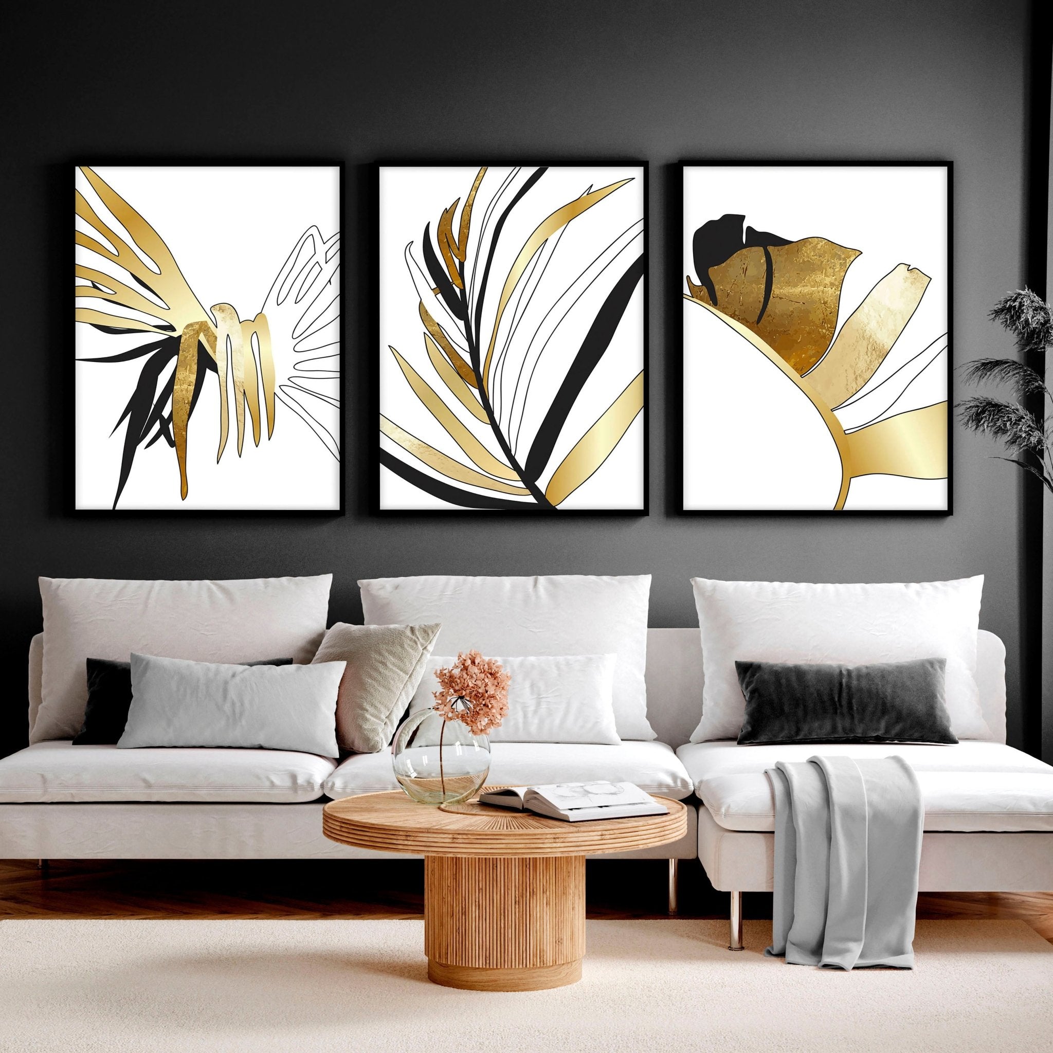 Set of 3 modern tropical wall art prints featuring elegant botanical designs in white, black, and gold, perfect for living room decor.