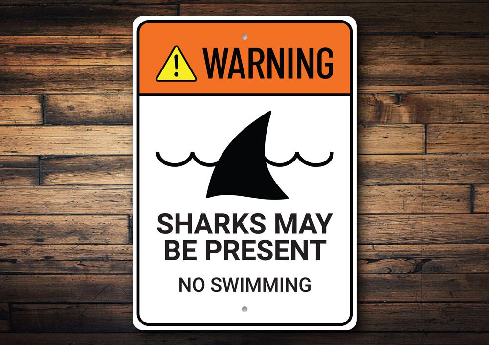 Warning Sharks Present Sign made of durable aluminum, featuring a vibrant beach-themed design, perfect for coastal decor.