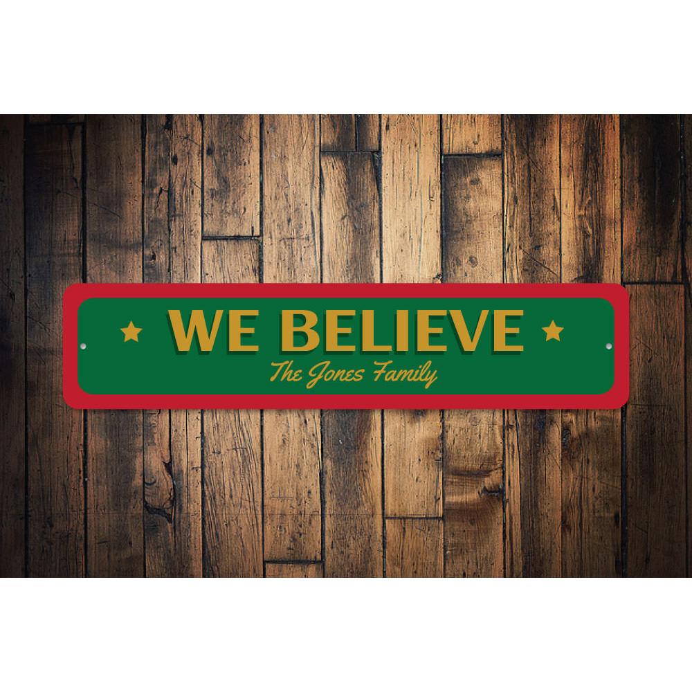 A festive 'We Believe Christmas' sign made of aluminum, featuring vibrant colors and a charming design, perfect for holiday decorations.