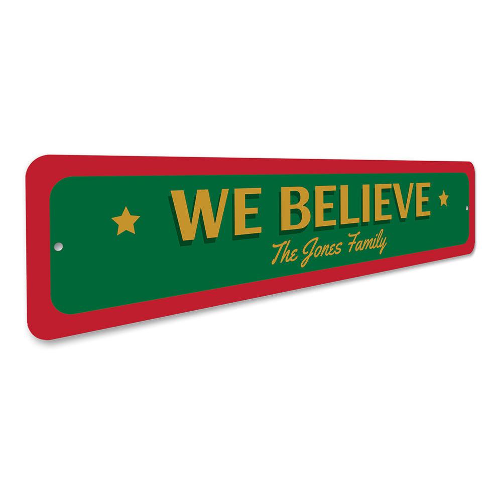 A festive 'We Believe Christmas' sign made of aluminum, featuring vibrant colors and a charming design, perfect for holiday decorations.