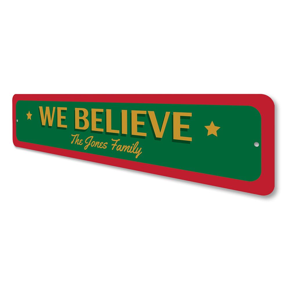 A festive 'We Believe Christmas' sign made of aluminum, featuring vibrant colors and a charming design, perfect for holiday decorations.