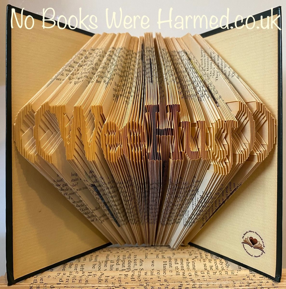 A handcrafted art piece called Wee Hug, made from folded pages of vintage books, showcasing unique colors and designs.