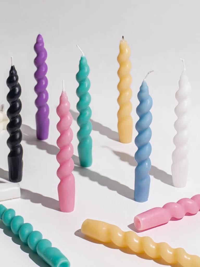 A colorful set of 7 whimsical twisty soy wax decorative candles arranged artistically, showcasing their unique shapes and vibrant colors.