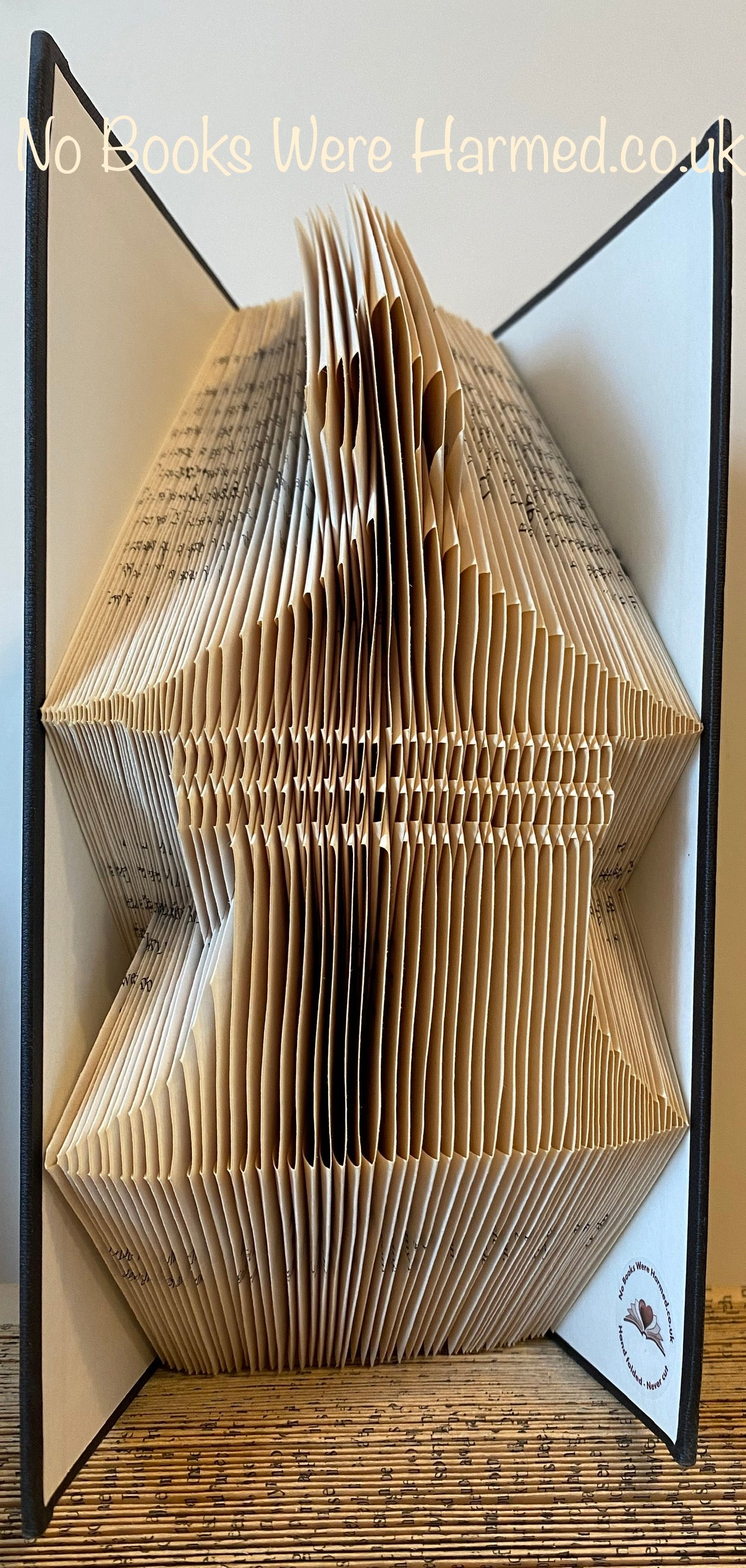 Hand-folded book art sculpture resembling a pagoda cupola, crafted from vintage books, showcasing intricate folds and unique textures.