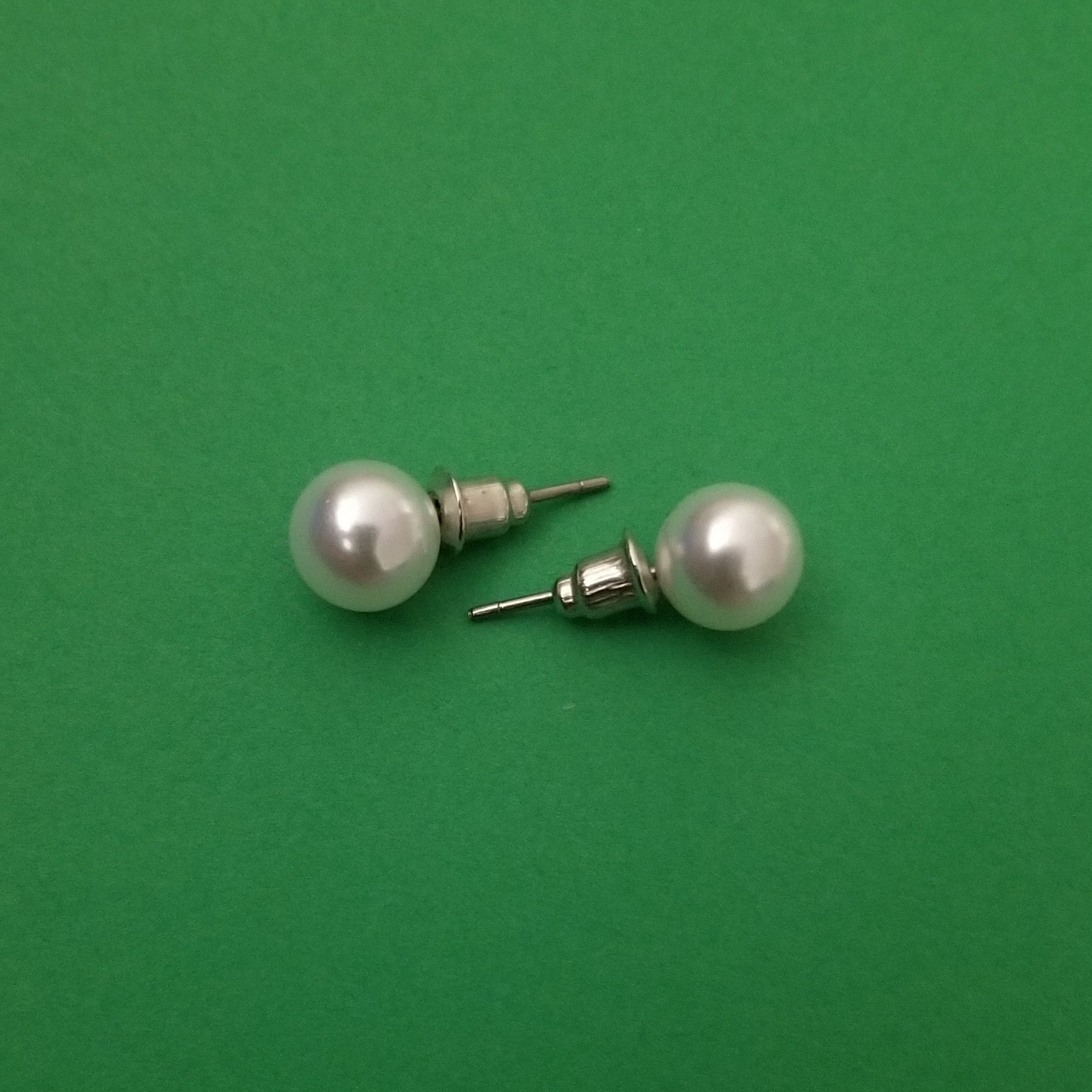 Elegant white imitation pearl studs displayed on a soft background, showcasing their lustrous finish and classic design.